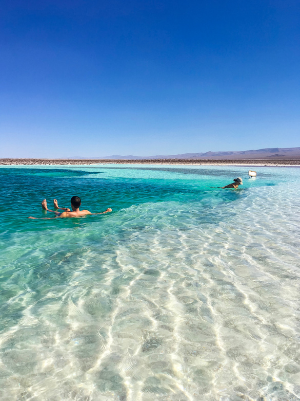 Unrecognizable travelers swimming in transparent ocean during summer vacation
